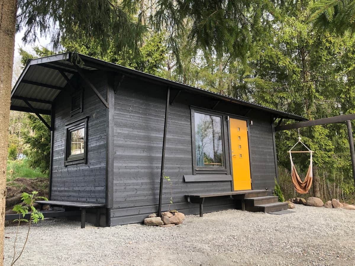 Inuti gula dörren — vitlackat tak, loft med två sängar, sittgrupp och köksdel.